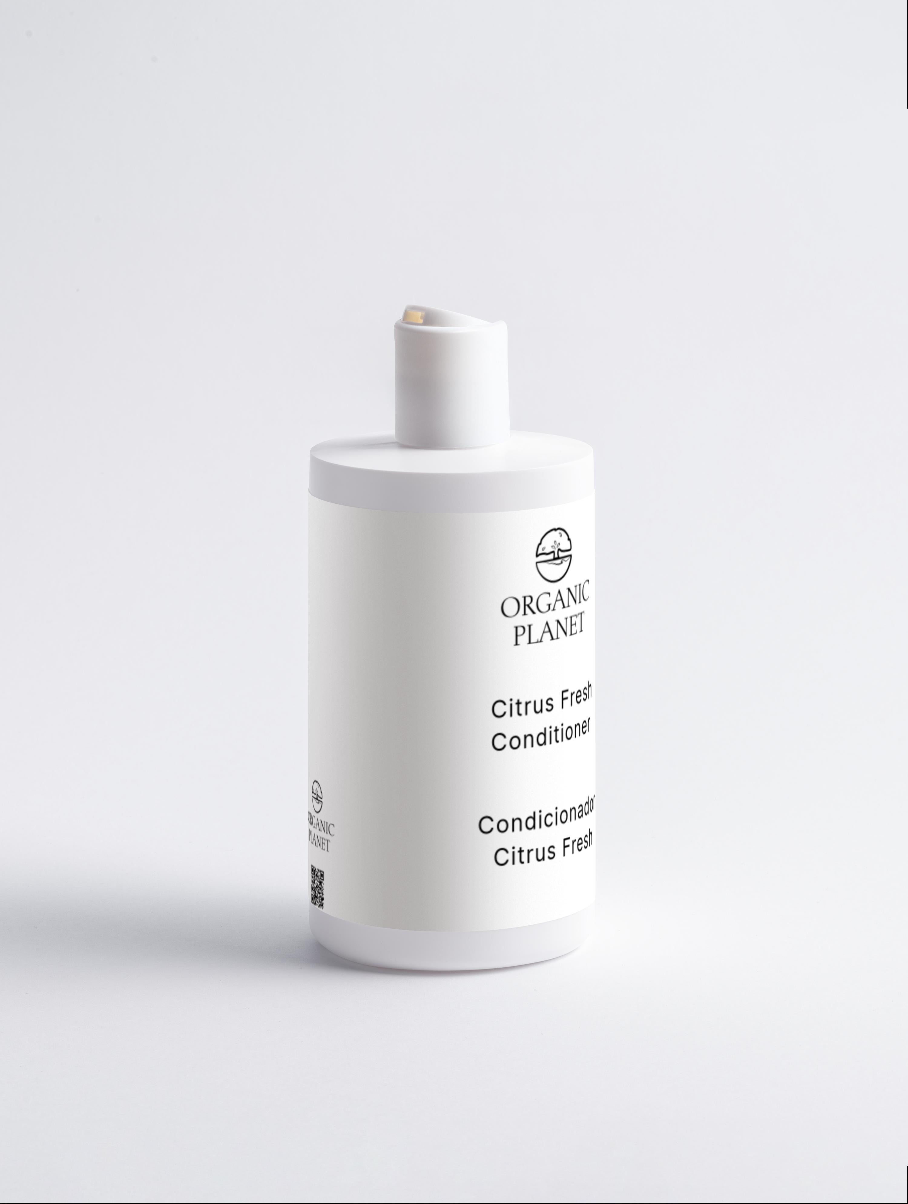White bottle of Organic Planet Citrus Fresh Conditioner on a light gray background. This conditioner nourishes and protects hair ends, reducing breakage and split ends. It helps hair feel silky, adds volume, and makes styling easier. Suitable for all hair types, it features a refreshing Citrus Cocktail.