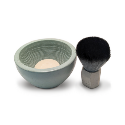 A green concrete shaving bowl next to a black shaving brush with a bar of soap inside the bowl. Elevate your shaving ritual with this artisan concrete bowl, meticulously crafted and finished with a sustainable, zero-VOC sealant. The strategically grooved surface whips soap into a rich, creamy lather while superior heat retention keeps your shave warm and comfortable. Hand-poured with distinctive character, it&