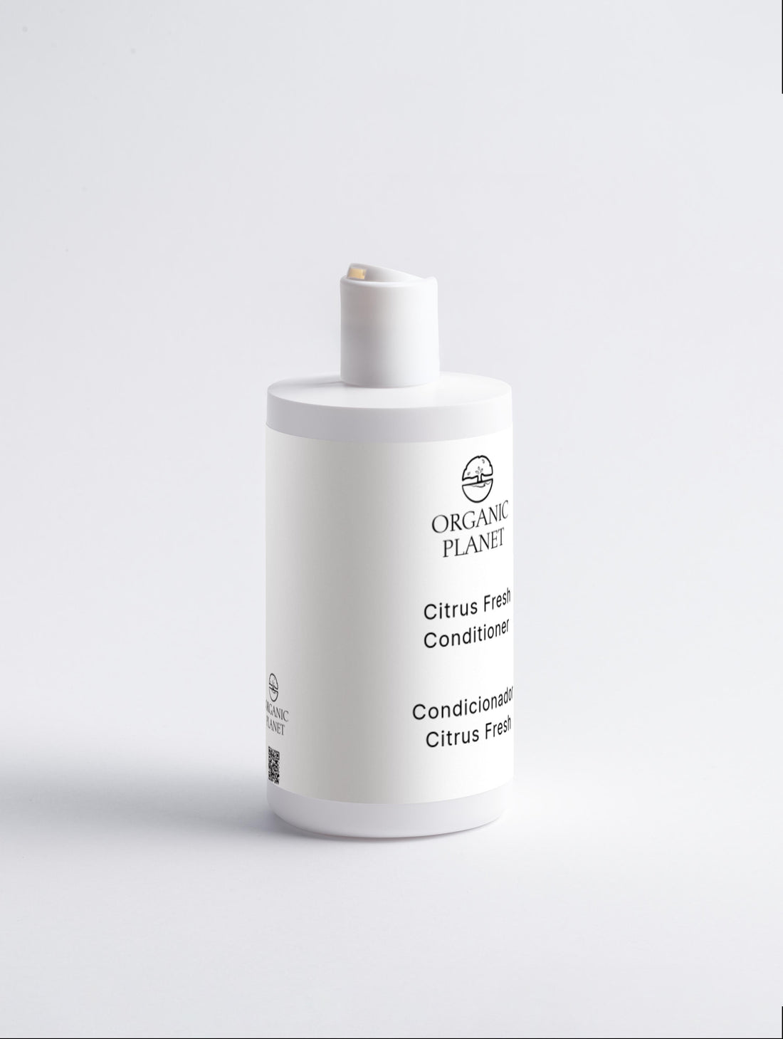 White bottle of Organic Planet Citrus Fresh Conditioner on a light gray background. This conditioner nourishes and protects hair ends, reducing breakage and split ends. It helps hair feel silky, adds volume, and makes styling easier. Suitable for all hair types, it features a refreshing Citrus Cocktail.