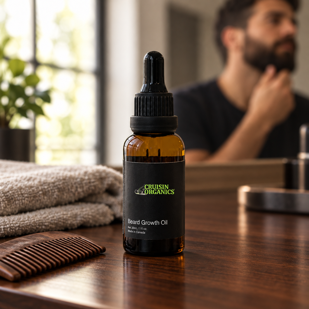 Cruisin Organics Beard Growth Oil bottle beside a comb and folded towels on a wooden vanity