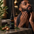Man massaging his beard beside Cruisin Organics beard oil and argan nuts on a stone counter