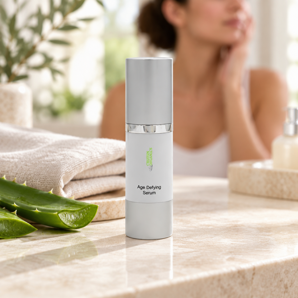 Age Defying Serum bottle on a stone vanity with linen and aloe leaf